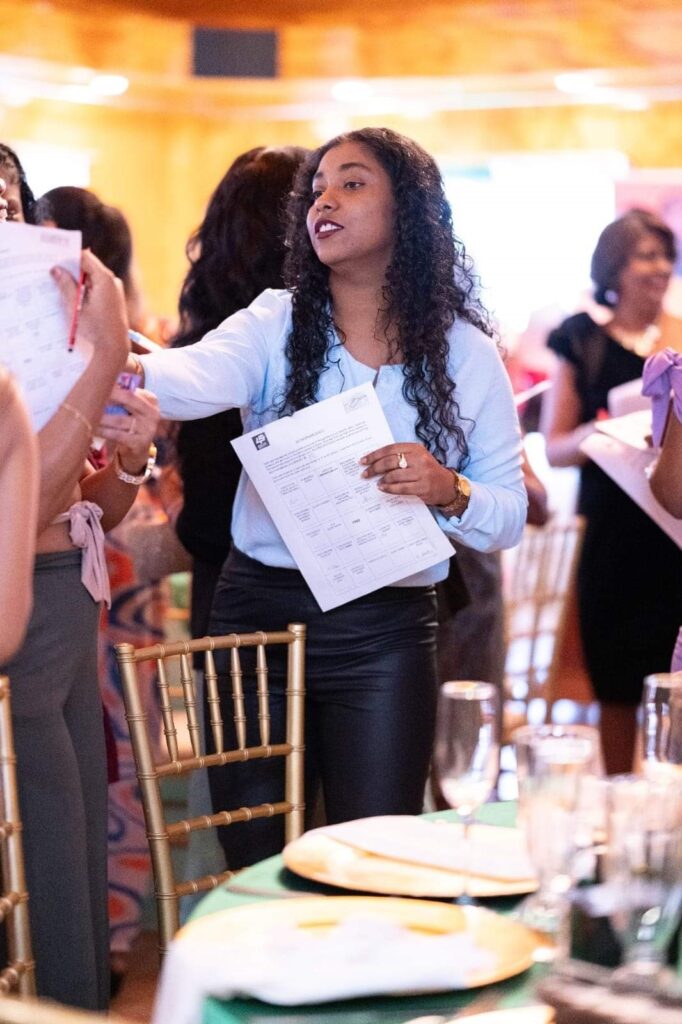 Shamela John handing out papers at a conference in a room full of women.